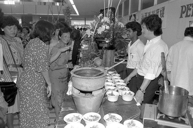 First Lady Mrs Wee Kim Wee visiting a food stall at the Christmas Fair organised by the Children's Charities Association at Singapore Conference Hall. Explaining to Mrs Wee is Violet Onn (second from left), a director of the fair.
