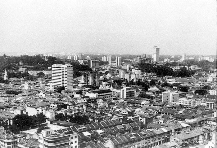 The junction of Middle Road and Victoria Street is in the centre of the photograph where the current location of National Library is. On the left is Fort Canning Hill, the spire of the Church of the Good Shepherd and the tall building is Tai Pan Ramada Hotel with National Museum building to the left of the hotel. The tall building under construction on the right is Mandarin Orchard Hotel.