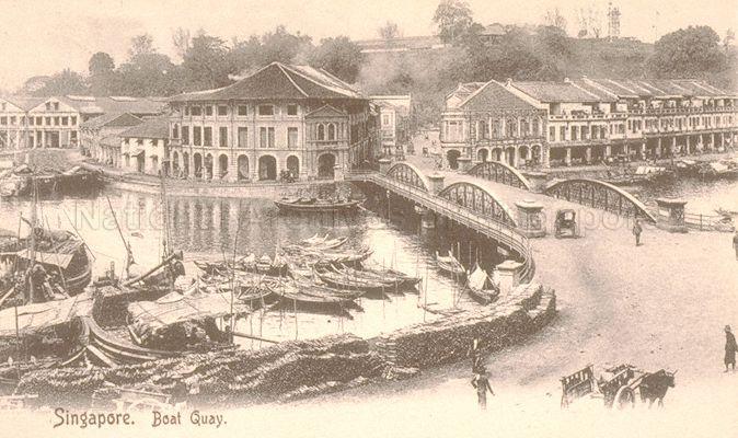 This is Merchant Bridge which was replaced by Read Bridge in 1889. The post card was being sold in post 1900s, 20 years after the bridge was completely changed. View of the Singapore River at the uppermost limit of Boat Quay, with Fort Canning Hill visible in the background.