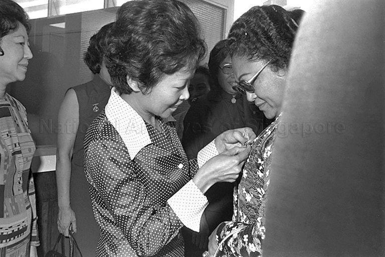 Mrs Lien Ying Chow (centre), President of the Girl Guides Association, pinning a Girl Guide Friendship Badge on Mrs Tien Suharto, wife of Indonesian President, during her visit to the Association while on a three-day state visit to Singapore