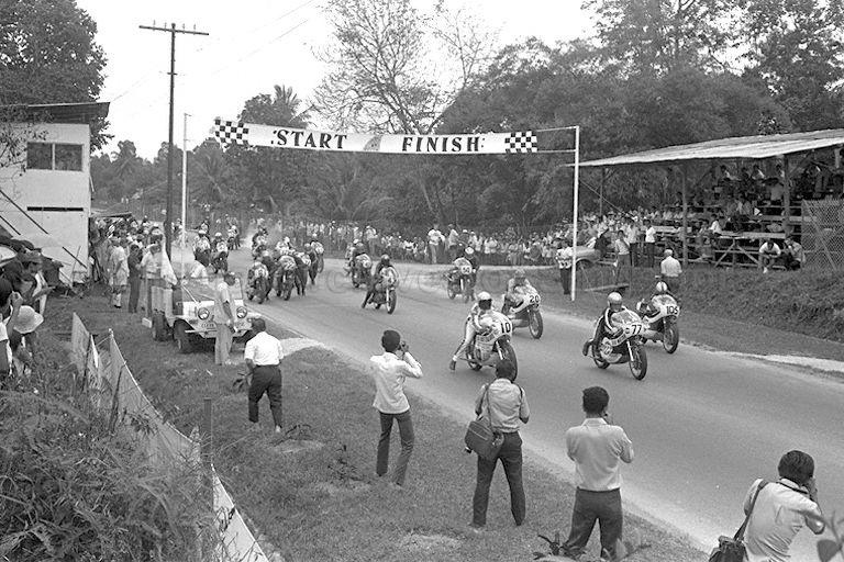 Start of the motorcycle race during the Singapore Grand Prix 1971 at Sembawang Hills Circuit. Also present are the track photographers.