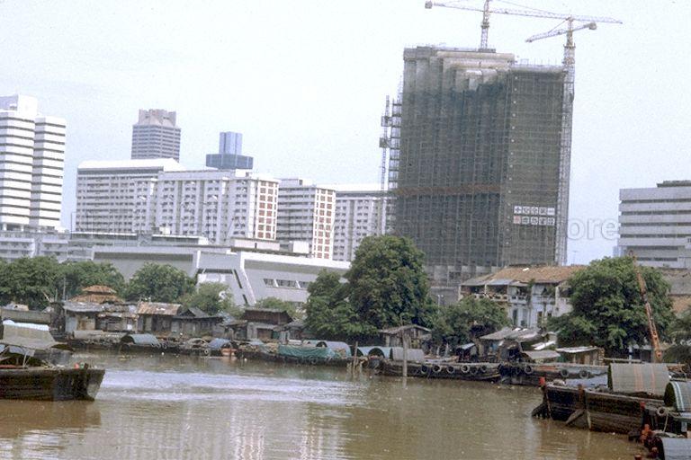 View of Singapore River and Furama Hotel under construction. Part of Fook Hai Building can be seen on the far left.
