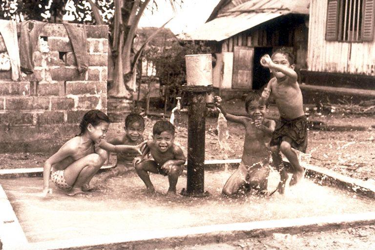 Children splashing themselves with water at a kampong (village) standpipe in Geylang Serai. Standpipes were installed in the 1960s by the government to provide water to residents who had no tap water in their houses.