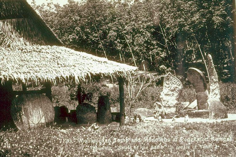 Muslim tomb and megaliths at Pengkalan Kempas, Negeri Sembilan, Federated Malay States. The 15th century tomb is believed to be the oldest Muslim grave in Malaya and was known as Keramat Sungai Udang in the old days. The three megaliths on the right were named, from left, 'rudder', 'spoon' and 'sword' due to their resemblance to the objects. The 'Shield of the Saint' is on the left.