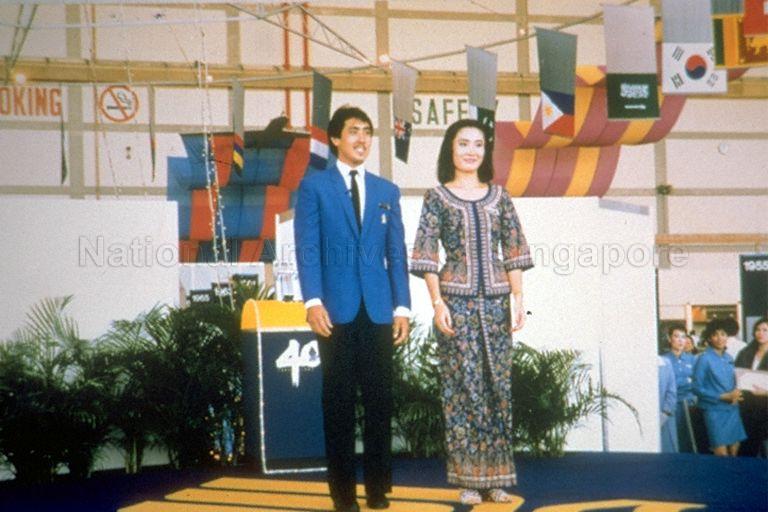 Singapore Airlines (SIA) flight stewardess wearing the Balmain-designed "Singapore Girl" sarong kebaya in blue, with flight steward wearing a complementary parisian-blue jacket