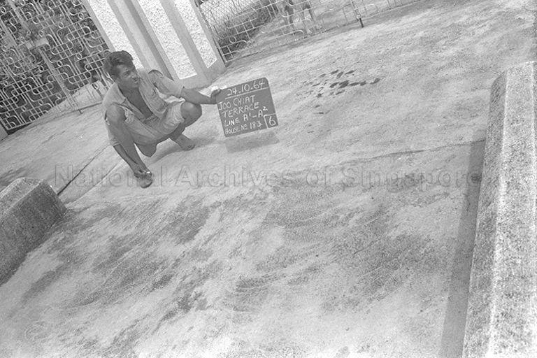 Public Works Department (PWD) worker holding a chalkboard outside House No. 183, Joo Chiat Terrace