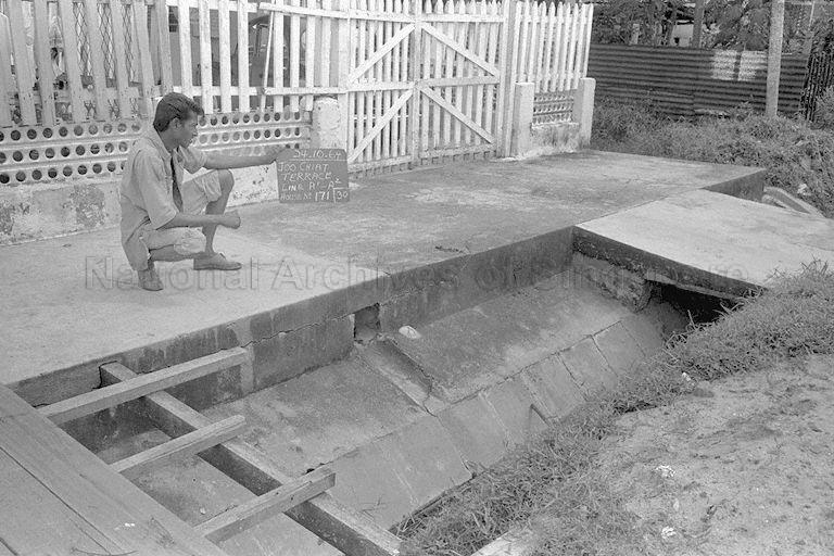 Public Works Department (PWD) worker holding a chalkboard outside House No. 171, Joo Chiat Terrace