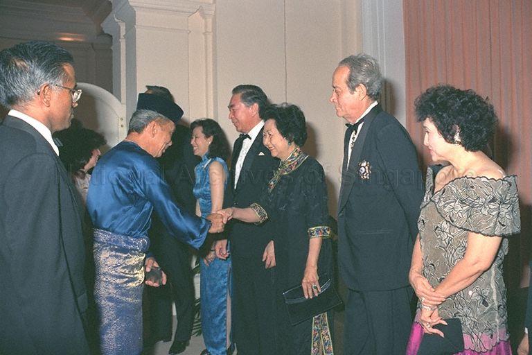 Wife of Speaker of Parliament Mrs Yeoh Ghim Seng welcoming Sultan Iskandar of Johor, the Yang di-Pertuan Agong, to state banquet at Istana. Lined from left are First Deputy Prime Minister and Minister for Defence Goh Chok Tong (mostly hidden), Mrs Goh, Dr Yeoh, Mrs Yeoh, Minister for Law E W Barker, and his wife Gloria. From the extreme left are Director of Protocol V K Rajan and the King's daughter Tunku Besar Zabedah. The King was in Singapore on a three-day state visit from 26-28 July, the first by a Malaysian King.