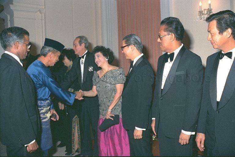 Mrs Gloria Barker, wife of Minister for Law E W Barker, welcoming Sultan Iskandar of Johor, the Yang di-Pertuan Agong, to state banquet at Istana. Lined from right are Minister for Communications and Information and Second Minister for Defence Dr Yeo Ning Hong; Minister for the Environment Dr Ahmad Mattar; Minister for Education Dr Tony Tan; Mrs Barker; Mr Barker; and Mrs Yeoh Ghim Seng, wife of Speaker of Parliament. At extreme left is Director of Protocol V K Rajan. The King was in Singapore on a three-day state visit from 26-28 July, the first by a Malaysian King.