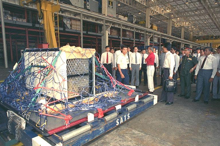 Malaysia's Yang di-Pertuan Agong of Malaysia, Sultan Iskandar of Johor (red shirt), watching how a live jaguar is packed for transport during his tour of Changi airport's cargo complex. Talking with the King (from left) are Chairman of Singapore Airport Terminal Services (Sats) and Deputy Chairman of Singapore Airlines (SIA) Lim Chin Beng (second, mostly hidden) and Second Deputy Prime Minister Ong Teng Cheong (third).