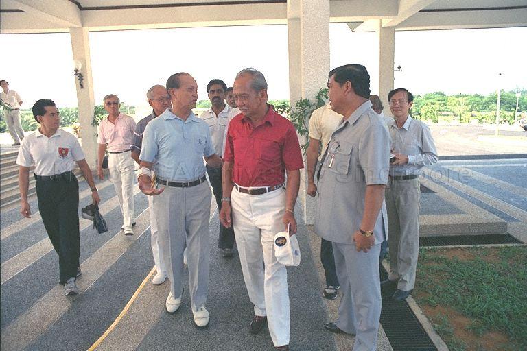 President Wee Kim Wee arriving at Tanah Merah Country Club for a game of golf with the Yang di-Pertuan Agong of Malaysia, Sultan Iskandar of Johor (red shirt). Behind Mr Wee is Vice-President of Singapore Golf Association Dennis Lee Kim Yew (grey striped shirt), while Malaysian Information Minister and minister-in-attendance Datuk Mohamed Rahmat (side view) is beside the King.
