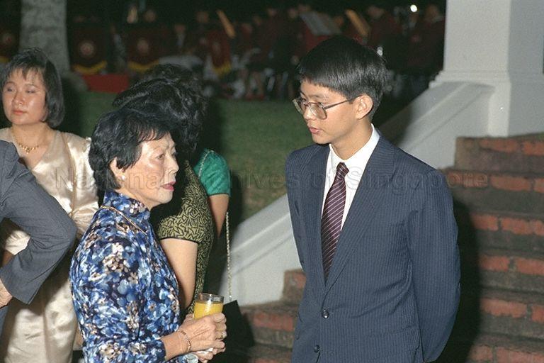 First Lady Mrs Wee Kim Wee talking with scholar Patrick Tan Boon Ooi during President's Scholarship awards presentation at Istana. Patrick, son of Minister for Education Dr Tony Tan, is pursuing a medical degree at Harvard University. At left is scholar Goh Li Meng who is reading medicine at National University of Singapore.