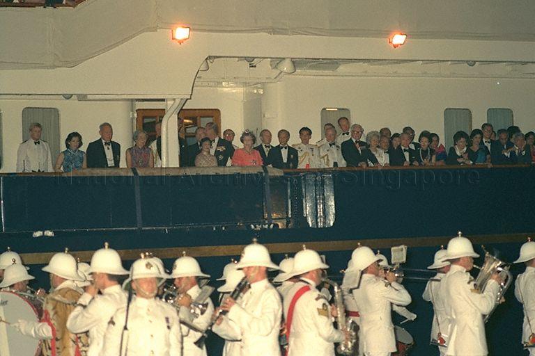 Her Majesty Queen Elizabeth II and her guests watching the traditional beating of the retreat performance on the dockside by the Band of Royal Marines from the royal yacht, HMY Britannia during the return banquet hosted by the Queen