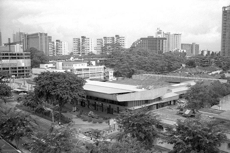 View of Orchard Road from Mandarin Hotel, showing Fitzpatrick's Supermarket (left) and to the extreme left is Lucky Plaza (a 30-storey shopping and residential building) under construction. In the foreground at the junction of Orchard Road and Bideford Road are Prince's Hotel Garni (extreme right) and the Orchard shopping complex, where the car showroom Orchard Motors (Singapore) Limited was located. The shopping complex housed the once popular Tivoli Coffee House.