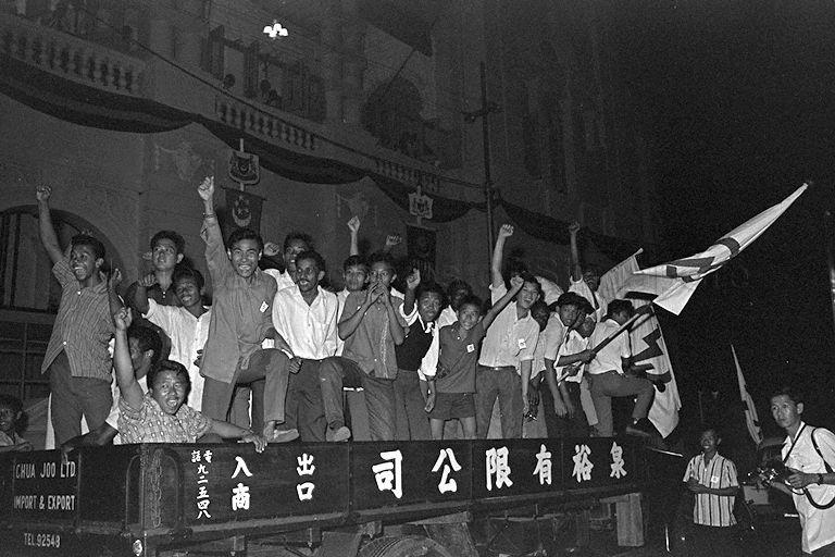 Supporters of People's Action Party (PAP) cheering and waving flags bearing PAP logo from a lorry during Legislative Assembly General Election 1963