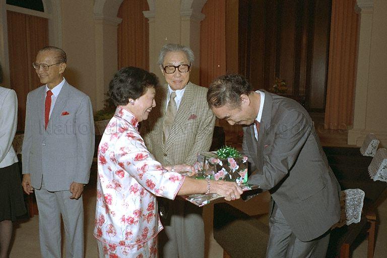 Ken Mori, husband of Japanese fashion designer Hanae Mori watches as First Lady Mrs Wee Kim Wee presents a souvenir to a member of the Japanese delegation during a courtesy call on President Wee Kim Wee (left) in the Istana
