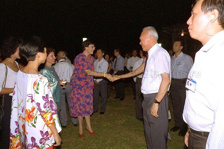 Mrs Mah Bow Tan, wife of Minister for Communications and Minister for the Environment, greeting Mrs Lee Kuan Yew (hidden) during National Day reception at Istana Lawn hosted by President and Mrs Wee Kim Wee. Among those looking on is Senior Minister Lee Kuan Yew.