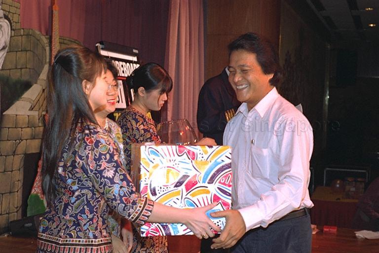 Mrs George Yeo (partially hidden), wife of Minister for Information and the Arts Brigadier-General (NS) George Yeo presenting a prize to a lucky draw winner at the Ministry of Information and the Arts (MITA) 1995 dinner and dance
