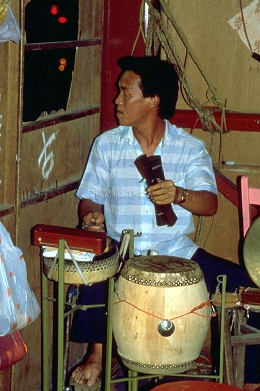View of Chinese wayang (opera) musician playing the guban (drum and clapper) at the back stage during an opera performance