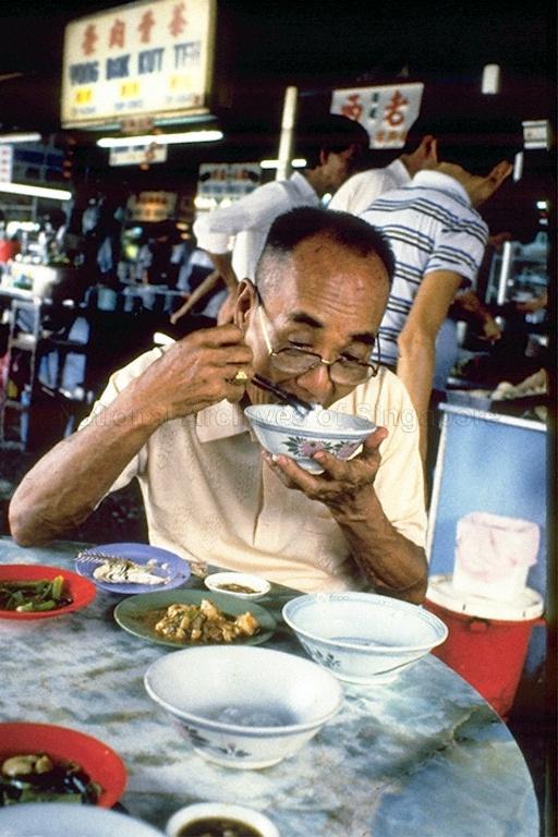 This man is taking Teochew Porridge (or often referred to as a poor man's meal) where the menu comprise, a bowl of porridge, a fish, salted vegetables, soya bean sauce, red chillies in vinegar and usually an extra bowl or two of plain porridge.