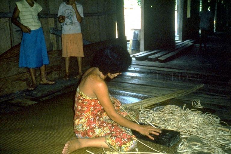 An Iban lady working with rattan on the ruai (common verandah)