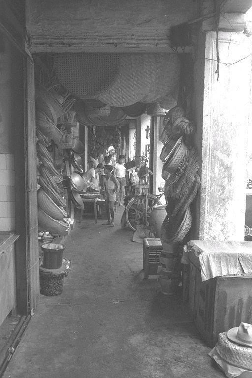 View of five-foot way with rattan baskets and sieves, iron woks and earthen stoves, and other wares hanging outside shops in Chinatown. An unique feature of Malaya's shophouses, "five-foot way" was introduced by the town planners when Sir Stamford Raffles stipulated that shophouses must have a covered walkway of about five feet along its street front. These walkways were meant to protect pedestrians from the hot tropical sun and rain. Business could be conducted along these five-foot ways and thus the phrase "five-foot-way traders".