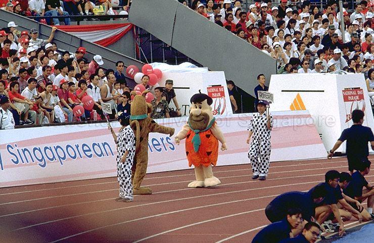 National Day Parade 1999 at National Stadium -- Two of four cartoon characters, Scooby Doo and Fred Flintstone, interacting with the crowd in pre-parade segment