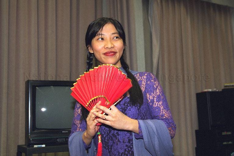 Lady in Malay dress holding Chinese fan at Gongxi Raya Celebration at Government Press Centre, Ministry of Information and the Arts, Port of Singapore Authority (PSA) Building. In 2000, Hari Raya Puasa was on 8 Jan and Chinese New Year was on 5 Feb.