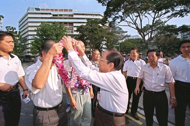 Member of Parliament for Marine Parade Group Representation Constituency (GRC) Goh Choon Kang (face hidden) being garlanded while accompanying Minister for Trade and Industry Brigadier-General George Yeo Yong-Boon on a walkabout in Braddell Heights Division of Marine Parade GRC