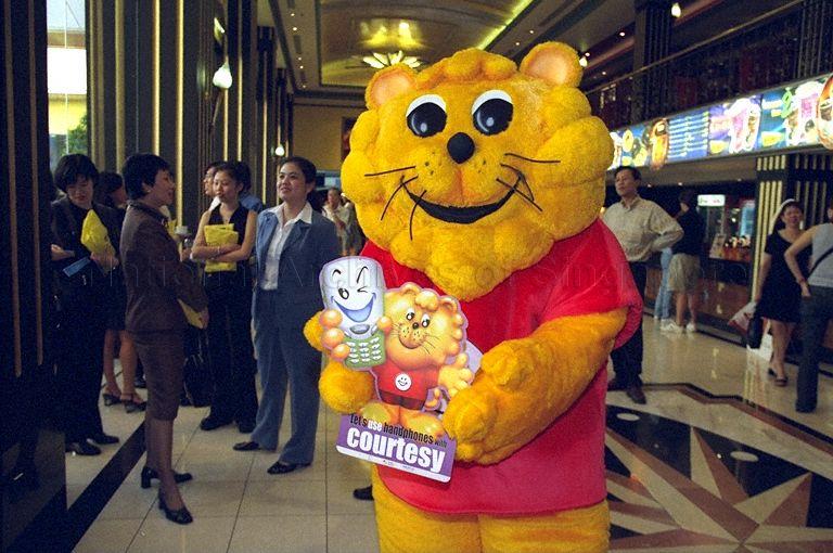 Singa the Courtesy Lion, mascot for Courtesy Campaign, holding poster showing this year's theme "Let's use handphones with courtesy" during launch of 22nd National Courtesy Campaign at Golden Village Grand cinema complex, Great World City