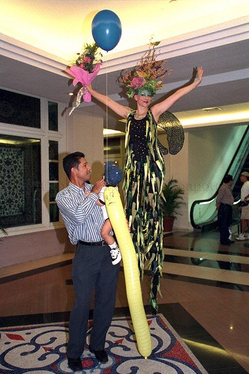 Stilt walker and passers-by at closing ceremony of Singapore River Buskers Festival 2000 at the Singapore River. First Lady Mrs Umi Nathan is guest of honour at this event.