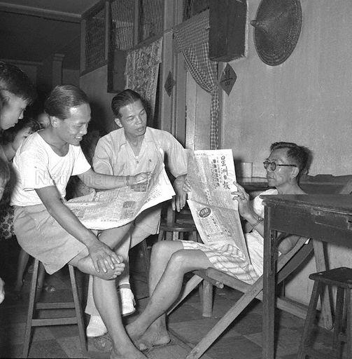 Men staying home in Chinatown during curfew hours. They are probably tenants renting rooms (entrance to which is draped with curtain) in a shophouse. Before establishment of the Housing and Development Board (HDB) in 1960, it was common to find single units partitioned into rooms for rent. Curfew was imposed for about ten days by the British colonial government at height of unrest caused by students and members of the Singapore Chinese Middle Schools Students' Union (SCMSSU) protesting against decision to dissolve the SCMSSU as a communist-front organisation and subsequent dismissal of teachers and students who had participated in subversive activities.