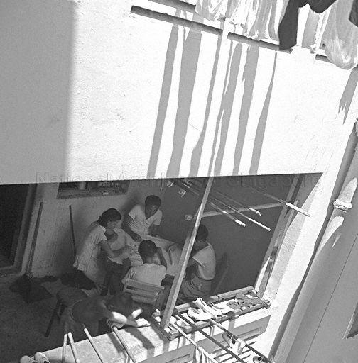 Residents of Singapore Improvement Trust (SIT) flats in Chinatown playing game of mahjong during curfew hours. Curfew was imposed for about ten days by the British colonial government at height of unrest caused by students and members of the Singapore Chinese Middle Schools Students' Union (SCMSSU) protesting against decision to dissolve the SCMSSU as a communist-front organisation and subsequent dismissal of teachers and students who had participated in subversive activities.