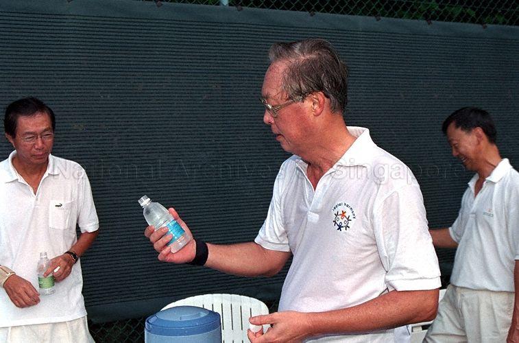 Prime Minister Goh Chok Tong holding a bottle of NEWater which he drinks and endorses after playing tennis with his friends at the Istana
