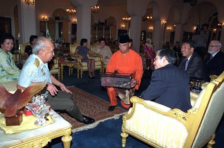 Sultan of Johore, Sultan Iskandar Ibni Almarhum Sultan Ismail (sitting second from left) about to show Minister for Education and Second Minister for Defence Teo Chee Hean, Minister, Prime Minister's Office and Second Minister for Foreign Affairs Lee Yock Suan, their wives  and other guests some items in a glass case at Istana Bukit Serene, Johore Bahru during Hari Raya celebration