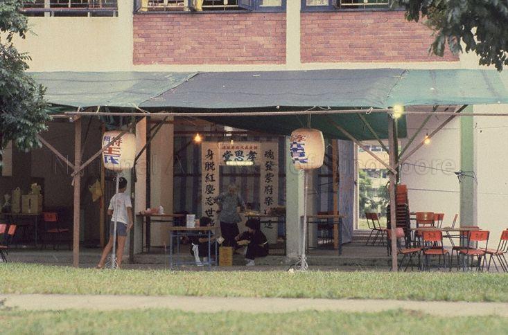 Funerals -- Void decks below Housing and Development Board (HDB) flats, like this one at Toa Payoh, are often used for holding Chinese wakes and funerals. The two white lanterns provide information on the deceased's name and gender (left) and age (right).