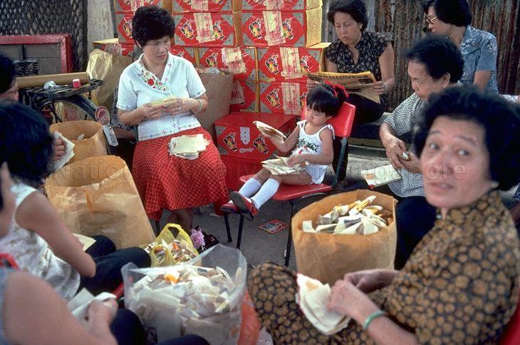 Women folding joss paper into shapes of gold and silver ingots as offerings during the &nbsp;Seventh Month Hungary Ghosts ceremony