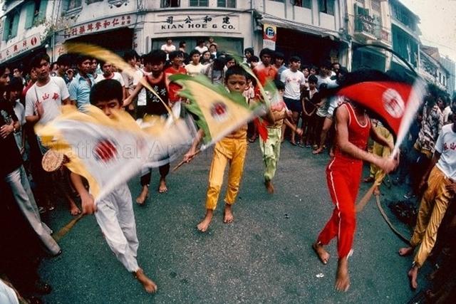 “Khor Kun" - Series of shots of the ceremonial dance performed by youths during a street procession through Telok Ayer Street. The prayers were also held at Chin Chew Street set up by 順風壇 in welcoming a procession along China Street.An altar set up by Soon Hong Tua 順風壇 at Chin Chew Street welcoming a procession of mediums along China Street and a group of young boys from 水炎宫 performing the Kao Jun, 犒军 ritual.