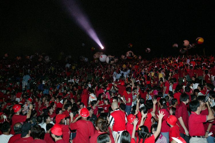 National Day Parade 2003 at National Stadium -- Some of 638 giant inflatable balls, each painted to resemble head of health-care and construction workers, bouncing down from top of spectator stands