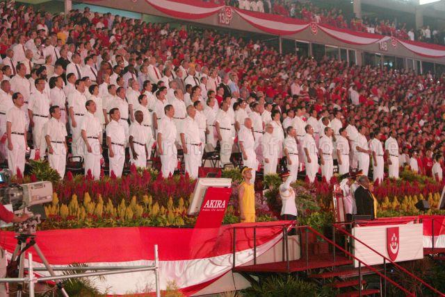 National Day Parade 2004 at the National Stadium -- View of President S R Nathan, Prime Minister Goh Chok Tong, Deputy Prime Minister and Minister for Finance Lee Hsien Loong, Minister for Law and Foreign Affairs Professor S Jayakumar, Minister for Home Affairs Wong Kan Seng, Minister for Trade and Industry George Yeo, Minister for National Development Mah Bow Tan, Minister in the Prime Minister's Office and Second Minister for Finance Lim Hng Kiang, Senior Minister Lee Kuan Yew, Deputy Prime Minister and Coordinating Minister for Security and Defence Dr Tony Tan, Minister in the Prime Minister's Office and Second Minister for Foreign Affairs Lee Yock Suan, Minister for Transport Yeo Cheow Tong, Minister for Information, Communications and the Arts Dr Lee Boon Yang, Minister in the Prime Minister's Office Lim Boon Heng, Minister for Defence Teo Chee Hean, Minister for Community Development and Sports and Minister in-charge of Muslim Affairs Dr Yaacob Ibrahim, Minister for Education Tharman Shanmugaratnam, Minister of State for Defence and National Development Cedric Foo, Minister of State for Foreign Affairs and Trade and Industry Raymond Lim, Minister of State for Education, and Community Development and Sports Chan Soo Sen, Senior Minister of State in the Prime Minister's Office Matthias Yao, Senior Minister of State for Law and Home Affairs Associate Professor Ho Peng Kee, Minister of State for Health and Transport Dr Balaji Sadasivan, Minister of State for Trade and Industry Dr Vivian Balakrishnan and members of Parliament singing the national anthem at the grandstand