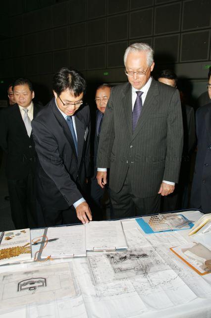 Project site manager Lim Chen Sian (front, left) briefing Senior Minister Goh Chok Tong during fundraising dinner in support of Fort Tanjong Katong Raising History Planting Roots Project at Suntec City Convention Centre