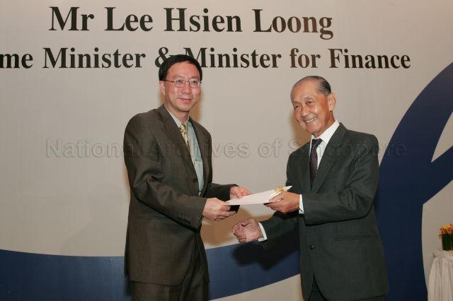Chairman of the Public Service Commission Dr Andrew Chew Guan Khuan presenting certificate of appointment/promotion to Permanent Secretary of Ministry of National Development Tan Tee How during annual dinner for the Administrative Service, the Civil Service's elite wing, at Conrad Centennial Singapore. Guest of Honour at the dinner was Prime Minister and Minister for Finance Lee Hsien Loong.