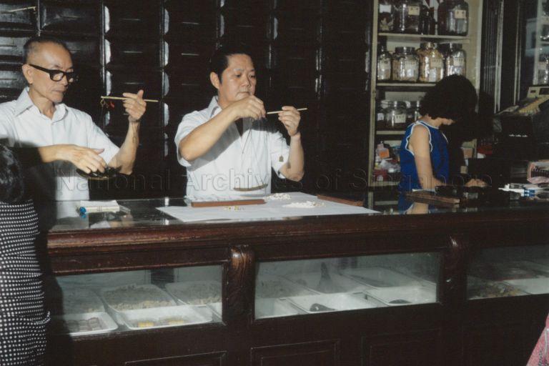 Men weighing Chinese medicinal herbs at the retail medicine department of Eu Yan Sang at South Bridge Road, Singapore. Eu Yan Sang is a famous traditional Chinese medicinal shop which began operations in the country in the 1910s, under the leadership of philanthropist Eu Tong Sen.
