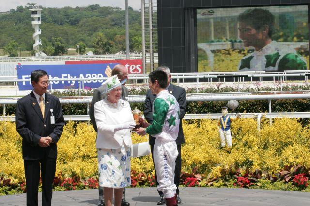 Queen Elizabeth II presenting the Queen Elizabeth II Cup to Richard Lim, Malaysian jockey of winning horse King and King, during her visit to Singapore Turf Club in Kranji. Looking on are Duke of Edinburgh Prince Philip, Chairman of Singapore Turf Club Koh Yong Guan (left) and Chairman of Singapore Totalisator Board Bobby Chin (right).