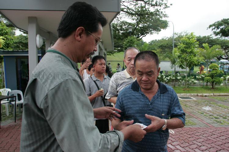 Official checking voter's poll card and identity documents at polling station situated in Bedok View Secondary School during Singapore General Election