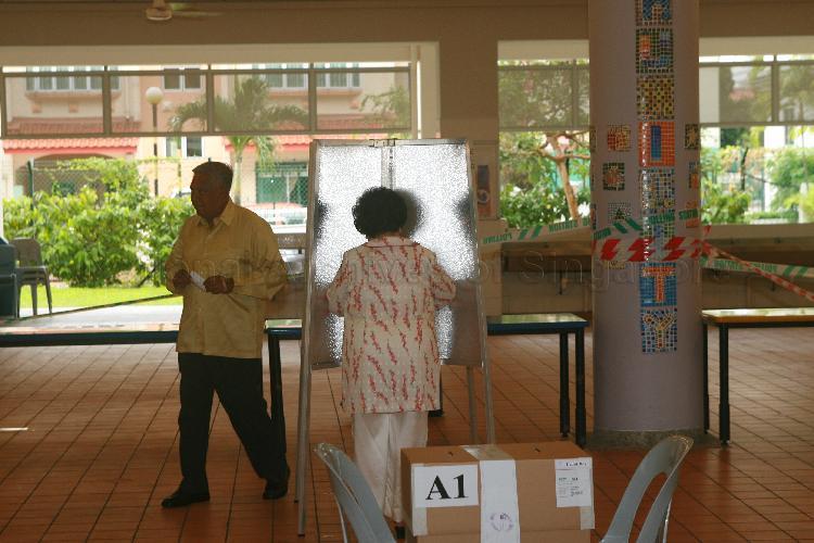 Mrs S R Nathan marking ballot paper at polling place, while President S R Nathan proceeds to cast his vote, at polling station situated in Haig Girls' School during Singapore General Election