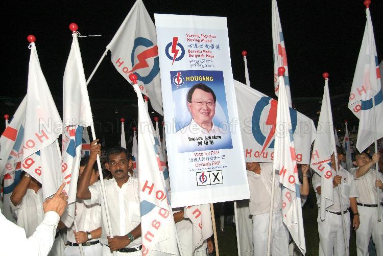 Supporters waving People's Action Party (PAP) flags and displaying poster of PAP candidate for Hougang Eric Low Siak Meng at Serangoon stadium, the assembly centre for PAP and their supporters during Singapore General Election