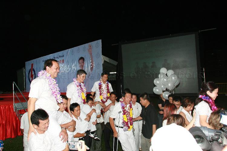 People's Action Party (PAP) candidate for Pasir Ris-Punggol Group Representation Constituency (GRC) Teo Chee Hean standing on crutches while his GRC team members Charles Chong You Fook (left), Michael Anthony Palmer and Ms Penny Low are being chaired by supporters at Woodlands stadium after their victory during Singapore General Election. The stadium was assembly centre for PAP and their supporters.