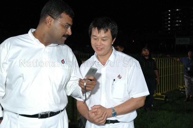 Former People's Action Party (PAP) Member of Parliament for Marine Parade Group Representation Constituency (GRC) Ravindran Ramasamy and fellow PAP member viewing messages/images on the mobile phone at Woodlands stadium, the assembly centre for PAP and their supporters during Singapore General Election