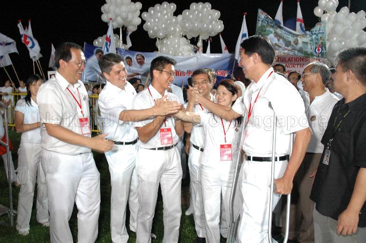 People's Action Party (PAP) candidates for Pasir Ris-Punggol Group Representation Constituency (GRC) Teo Chee Hean (on crutches), Ms Penny Low, Dr Ahmad bin Mohamed Magad, Teo Ser Luck, Michael Anthony Palmer and Charles Chong You Fook (left) gesturing teamwork with their hands at Woodlands stadium, the assembly centre for PAP and their supporters during Singapore General Election